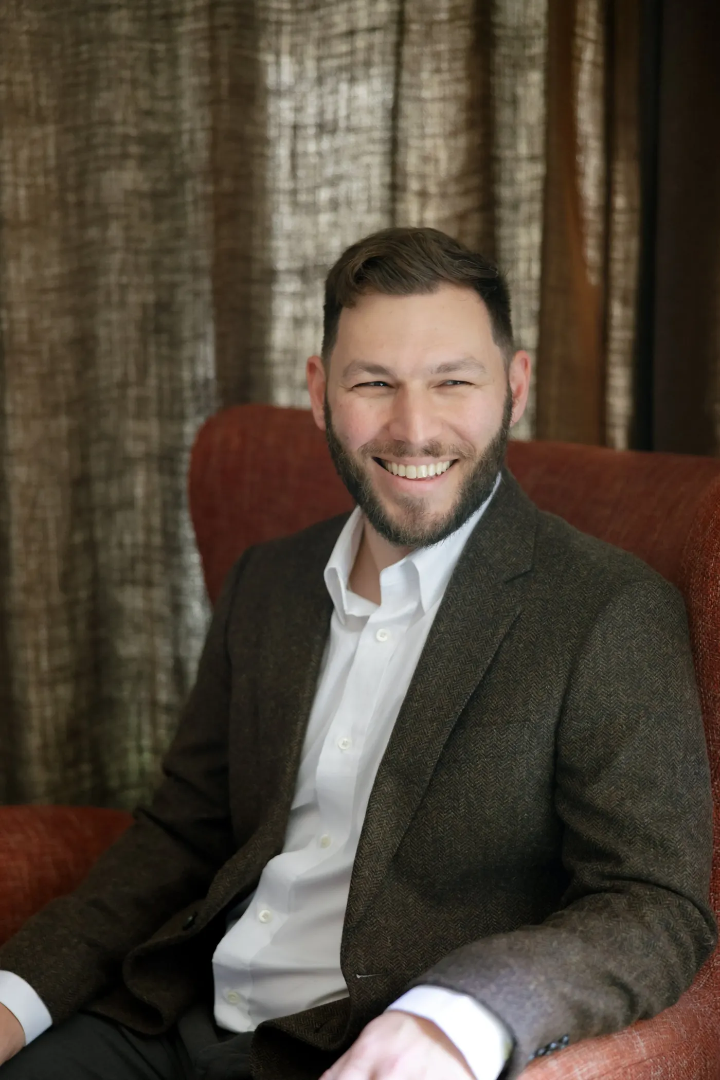 Michael Robin, smiling, seated in a red armchair